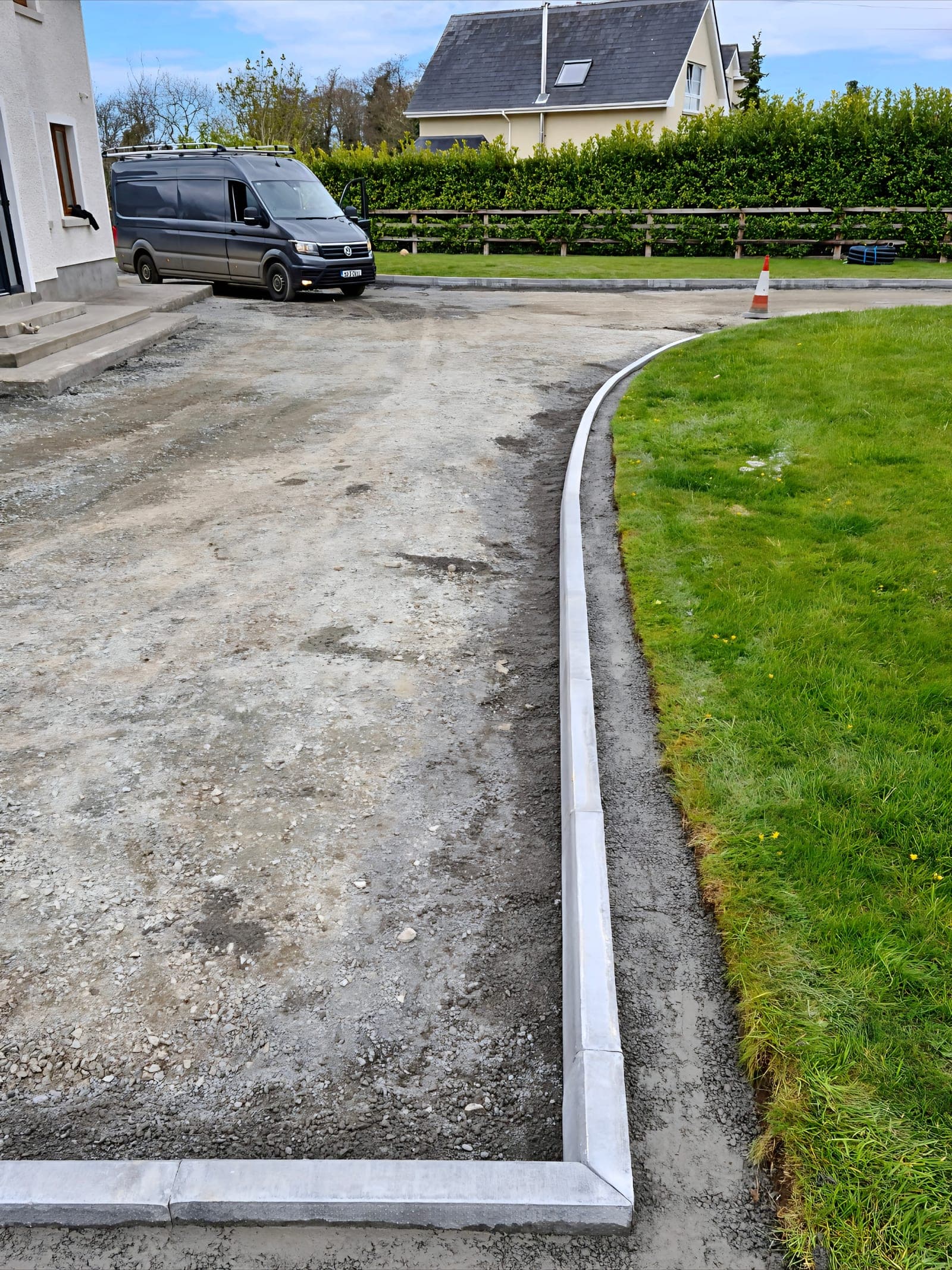 Compacted driveway sub-base with freshly laid concrete kerb edging and wet haunching