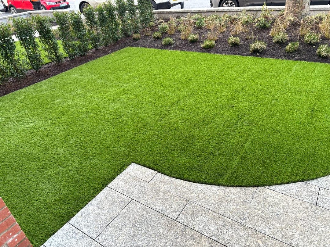 Front garden artificial lawn meeting granite paving on a sweeping curved edge